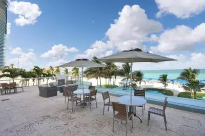 a group of tables and chairs with umbrellas on the beach at Beachfront Resort Pool Ocean View Balcony Gym in Aventura