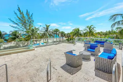a patio with chairs and tables and palm trees at Beachfront with direct beach access and amazing views in Aventura