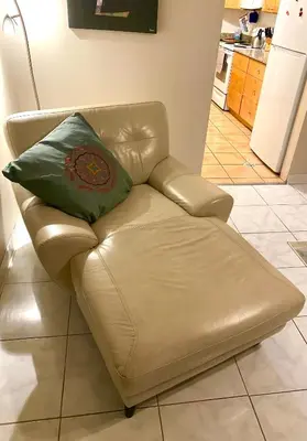 a brown leather couch with a green pillow on it at Judit’s in Dania in Dania Beach