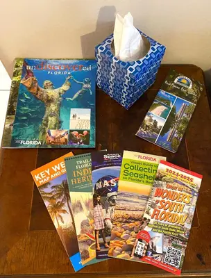 a table topped with magazines and a box of tissues at Judit’s in Dania in Dania Beach