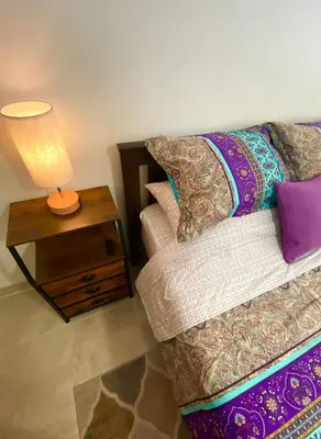 a bed with a table with a lamp on it at Judit’s in Dania in Dania Beach