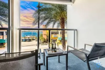 a balcony with a chair and a table and a palm tree at Condo Bay View Infinity Pool Beach Service in Hollywood