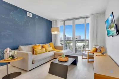 a living room with a white couch and a blue wall at Modern 2 BR - Beachwalk Resort - Pool - Gym in Hallandale Beach