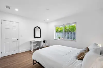 a white bedroom with a bed and a desk at Sailors Rest @ Sailboat Bend in Fort Lauderdale