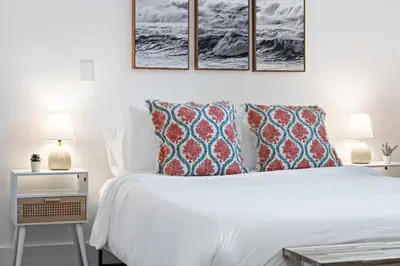 a bedroom with a white bed with four pictures on the wall at Sailors Rest @ Sailboat Bend in Fort Lauderdale