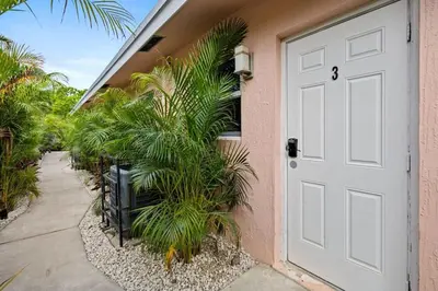 a white door on a pink house with palm trees at Spacious 2 BR @Sailboat Bend in Fort Lauderdale