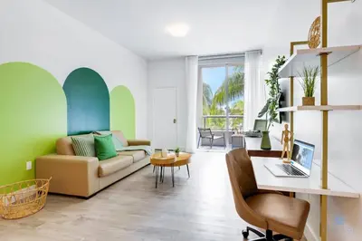 a living room with a couch and a desk with a laptop at Modern Luxury Retreat: Rooftop Pool Ocean Views in Hollywood