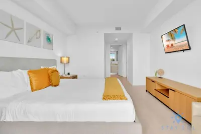 a white bedroom with a large bed and a dresser at Modern Condo - Amazing Pool - Gym - Balcony in Hallandale Beach