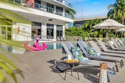 a pool with chaise lounge chairs and a table and a swimming pool at Modern Condo - Amazing Pool - Gym - Balcony in Hallandale Beach