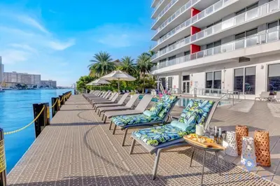 a row of chaise lounge chairs next to a building at Modern Condo - Amazing Pool - Gym - Balcony in Hallandale Beach