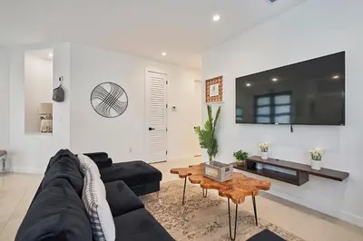 a living room with a black couch and a table at Modern New Construction Villa in Hollywood