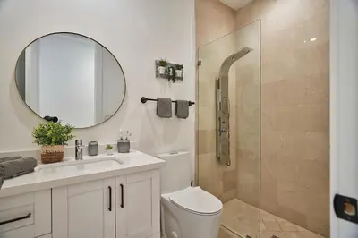 a bathroom with a toilet and a shower with a mirror at Modern New Construction Villa in Hollywood