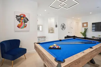 a living room with a pool table and a blue chair at Modern New Construction Villa in Hollywood