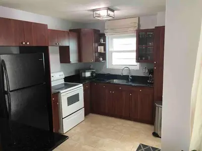 a kitchen with wooden cabinets and a black refrigerator at South Beach One Bedroom Condo with Parking Spot in Miami Beach