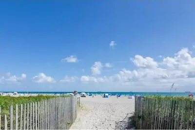 a person standing on a beach near a fence at South Beach One Bedroom Condo with Parking Spot in Miami Beach