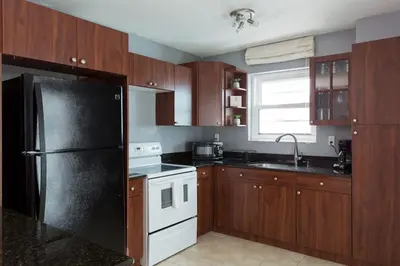 a kitchen with wooden cabinets and a black refrigerator at South Beach One Bedroom Condo with Parking Spot in Miami Beach