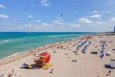 a beach with a bunch of people on the sand and the ocean at Cozy South Beach 1BR Apt Near Beach & Ocean Drive in Miami Beach