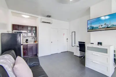 a living room with a couch and a desk and a kitchen at Chic Large Studio Apt Near Ocean Drive South Beach in Miami Beach