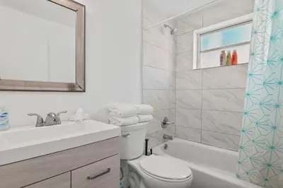 a white bathroom with a sink and a toilet at Balcony Chic Apt, w/2 Queenbeds, on Ocean Dr Beach in Miami Beach