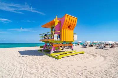 a lifeguard tower on a beach with chairs and umbrellas at Ocean Drive Comfy apt, w/2 Queen Beds by the Beach in Miami Beach