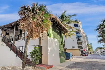 a building with a palm tree next to a street at Beach Condo 2BR & Efficiency Combo on Hollywood Beach in Hollywood