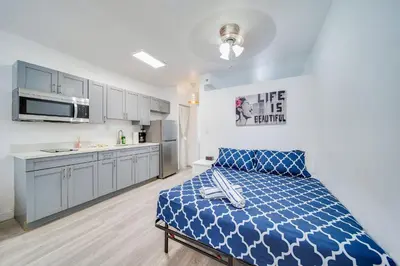 a bedroom with a blue bed and a kitchen at Beachside 1 b/r, w/2 Queen Beds, Ocean Drive SOBE in Miami Beach