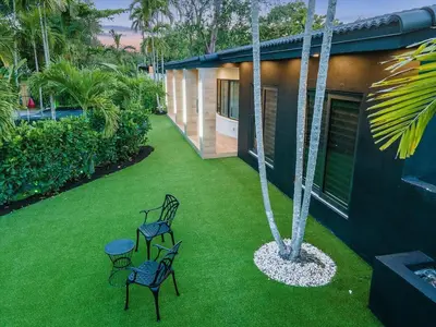 a yard with two chairs and a palm tree at VillaKOBO Heated pool Spa Golf Tennis crocodile in Miami