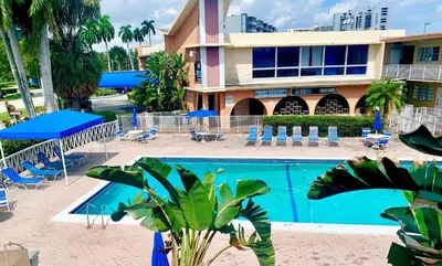 a pool in front of a hotel with chairs and umbrellas at Walk to the beach, Studio, with Pool and FREE Parking in Hallandale Beach