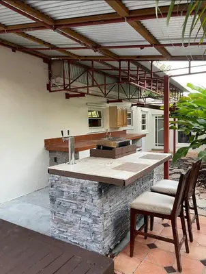 an outdoor kitchen with a stone counter and chairs at CHEERFUL PRIVATE ROOM 2 MILES AWAY FROM SUNNY ISLES BEACH in North Miami Beach