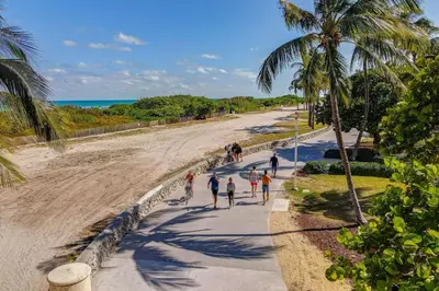 a group of people walking on a sidewalk next to the beach at Deco Apt w/2 Queen Beds on Ocean Dr, South Beach in Miami Beach