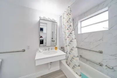 a white bathroom with a sink and a mirror at Deco Beachside Apt, w/2 Queen Beds, Washer/Dryer in Miami Beach