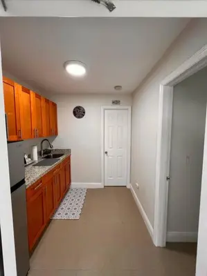 a kitchen with wooden cabinets and a sink and a door at Casita Cafe in Miami