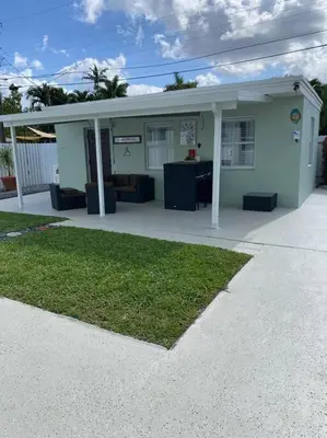 a small white building with a porch and grass at Casita Cafe in Miami