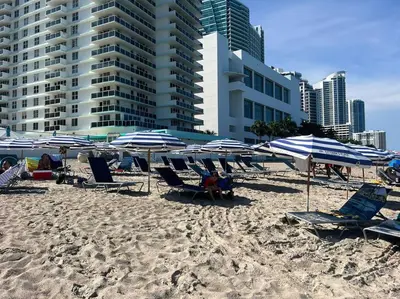 a group of chairs and umbrellas on a beach at Sunny Mornings & 2 Full Beds, BeachWalk Studio in Hallandale Beach