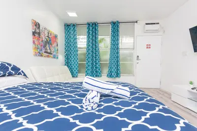 a bedroom with a blue and white bed with blue curtains at Ocean Drive Deco Apt w/2 Queen Beds, Steps 2 Beach in Miami Beach
