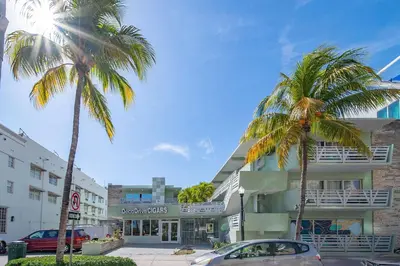 two palm trees and a car parked in front of a building at Ocean Drive Deco Apt w/2 Queen Beds, Steps 2 Beach in Miami Beach