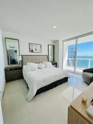 a white bedroom with a bed and a large window at Soñada vista al agua 3/3 in Miami