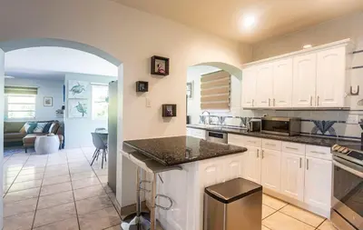 a kitchen with white cabinets and a living room at Surfers Cove - Modern 3 2 w Pool near Calle 8 in Miami