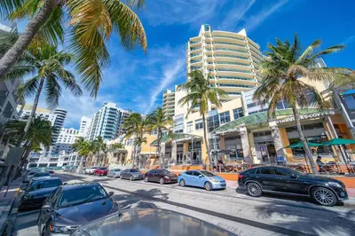 a city street with parked cars and palm trees at Steps 2 Beach, Prime Ocean Dr Condo w/2 Queen Beds in Miami Beach