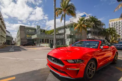 a red car is parked in a parking lot at Private Ocean Dr Apt w/2 Queen Beds, Steps 2 Beach in Miami Beach