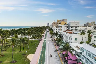 an empty city street with palm trees and the ocean at Stylish Ocean Dr Apt w/ 2 Queen Beds, Across Beach in Miami Beach