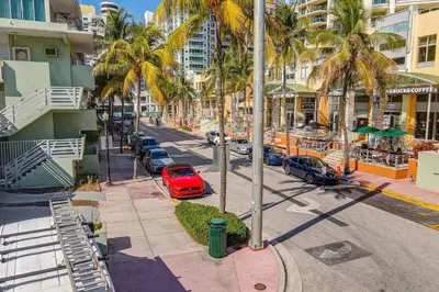 a red car parked on a street with palm trees at Sunny Ocean Dr Condo, w/2 Queen Beds, South Beach in Miami Beach
