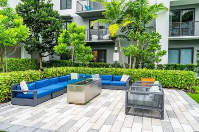 a patio with blue couches in front of a building at Tranquil 1 Bed Escape in Doral With Free Parking in Hialeah Gardens