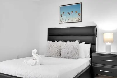 a bedroom with a white bed with a black headboard at Charming 3-Bed Mins from Brickell With Free Parking in Miami
