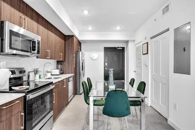 a kitchen with a glass table and green chairs at Gorgeous 3-Bed Retreat Mins from Bayside and Parking in Miami