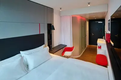 a bedroom with a white bed and a red chair at citizenM Miami South Beach in Miami Beach