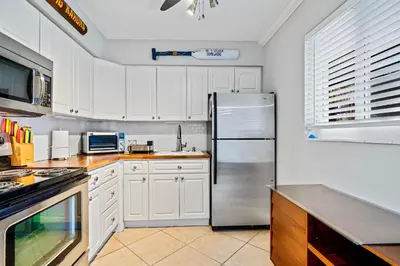 a kitchen with white cabinets and a stainless steel refrigerator at Wilton Manors 2BR Charm! Walk to the Drive in Fort Lauderdale