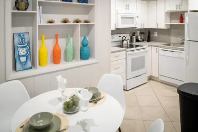 a kitchen with white cabinets and a white table and chairs at Walk to Wilton Drive - Spacious & Quiet Villa #1 in Fort Lauderdale