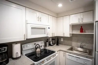 a kitchen with white cabinets and a stove and microwave at Walk to Wilton Drive - Spacious & Quiet Villa #1 in Fort Lauderdale