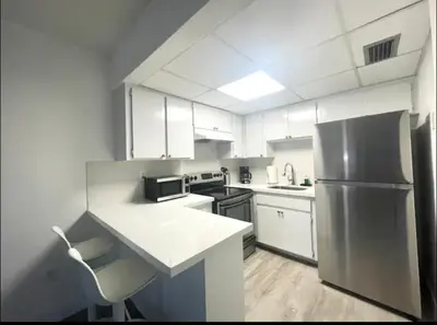 a kitchen with white cabinets and a stainless steel refrigerator at Miami International Airport 2 in Miami